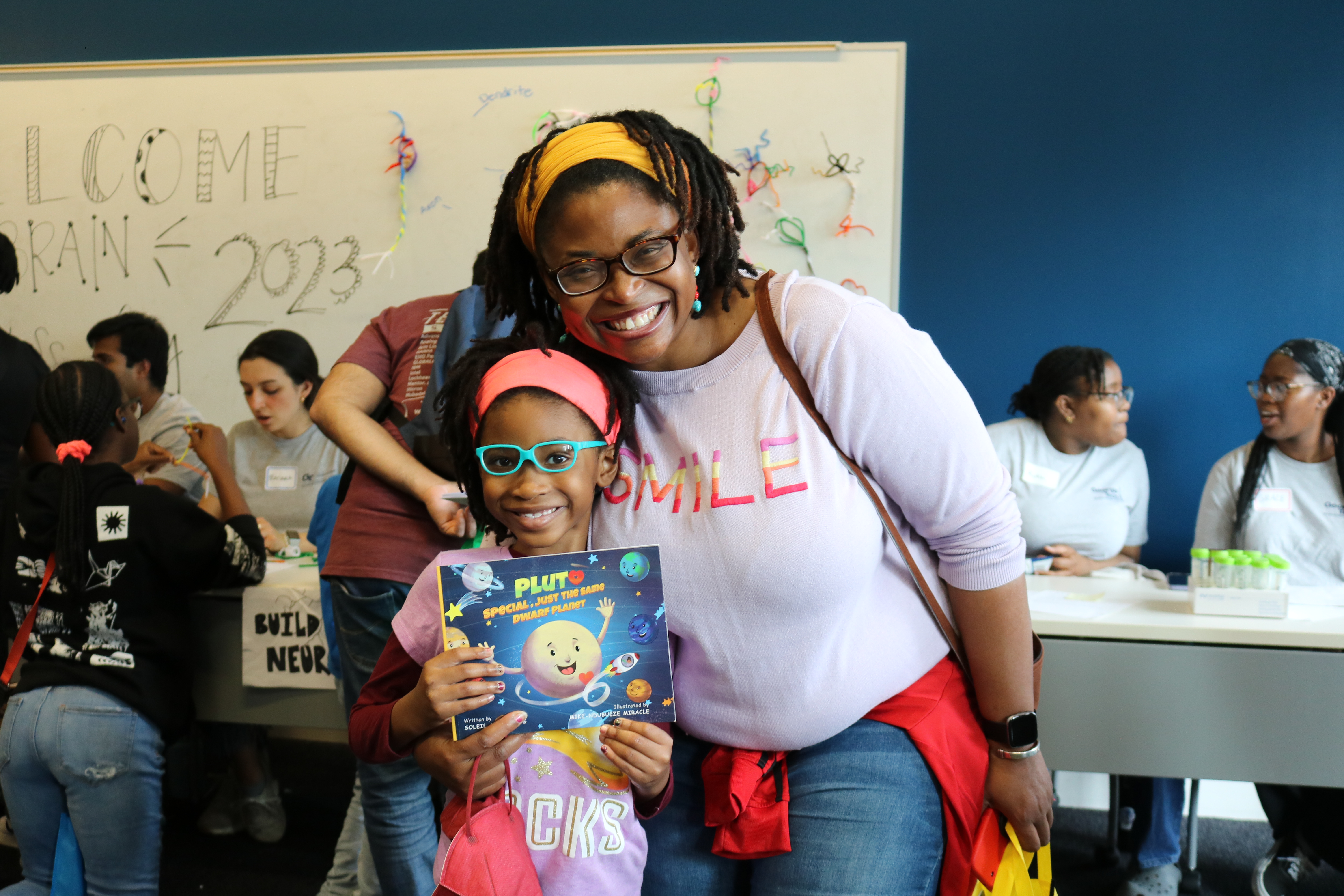 Young author Soleil A. Cross holds her book, Pluto, Special, Just the Same Dwarf Planet, as she explores the Brain Games exhibit with her mom during the 2023 Georgia Tech Science and Engineering Day. (Photo Jess Hunt-Ralston)