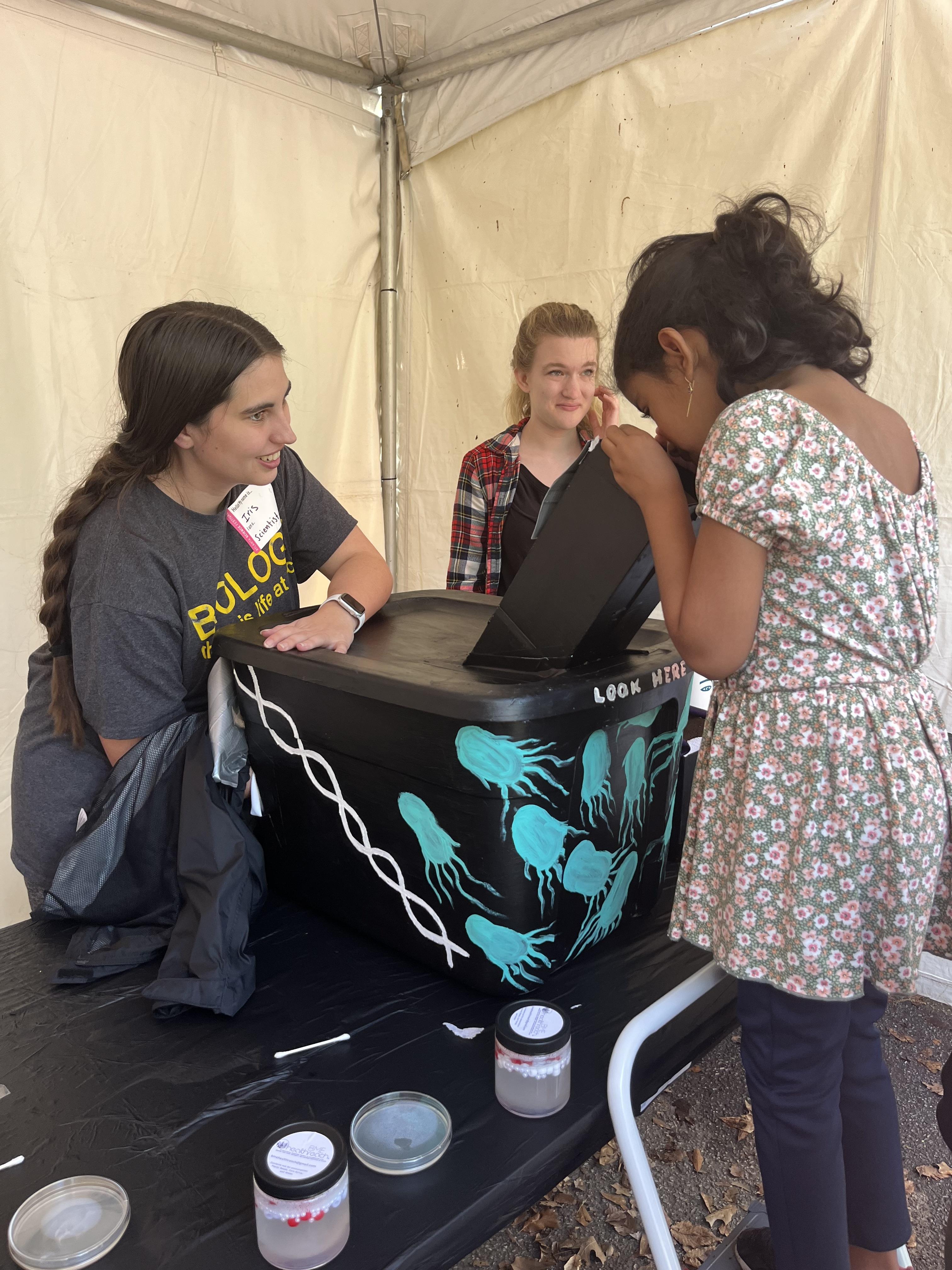 Microbiology Ph.D. student Iris Irby shows attendees glowing bacteria at an Exploration Expo booth hosted by the Center for Microbial Dynamics and Infection. (Photo Jess Hunt-Ralston)